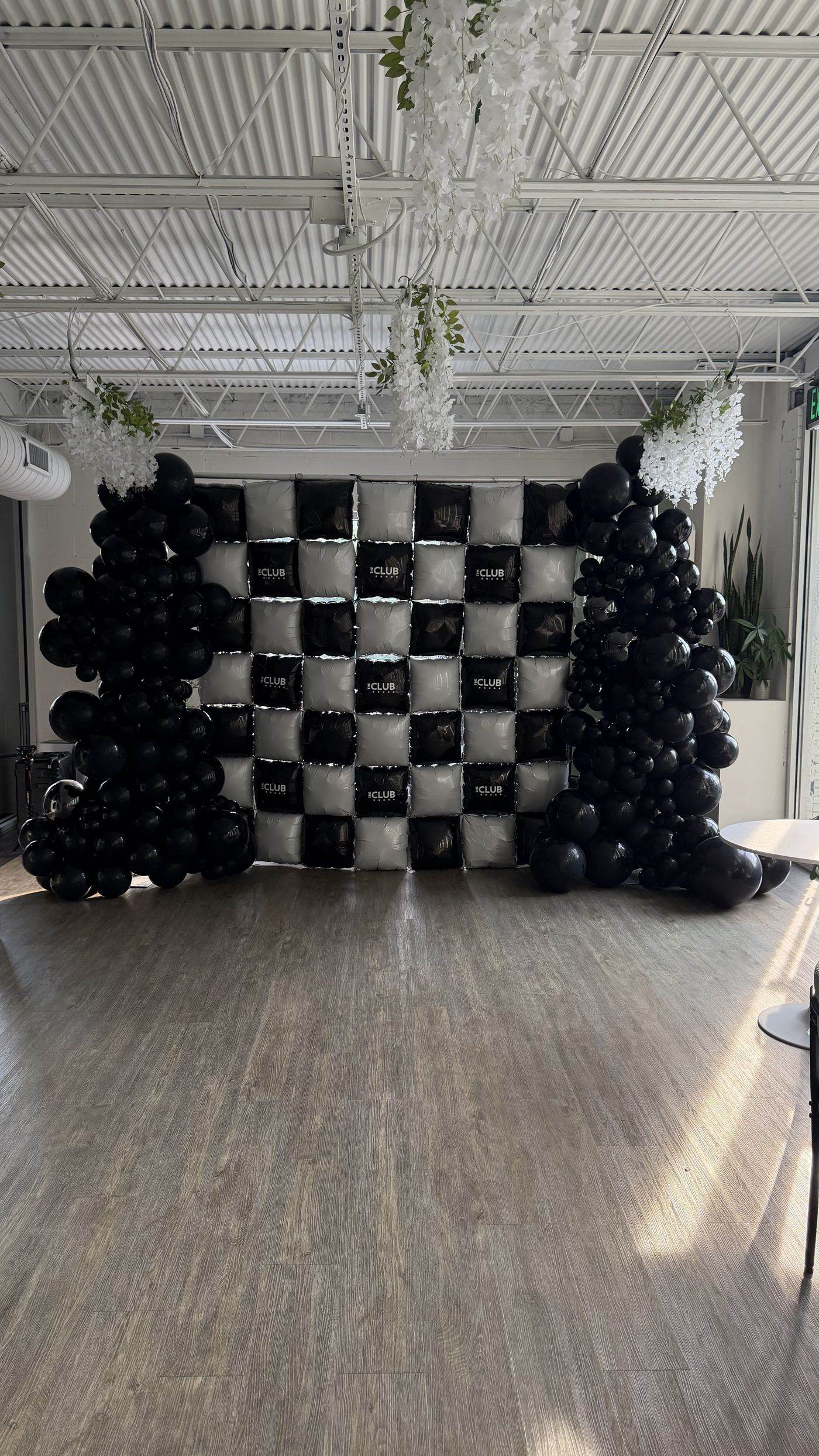 Custom black and white checkerboard balloon wall for The Club Wellness Hub