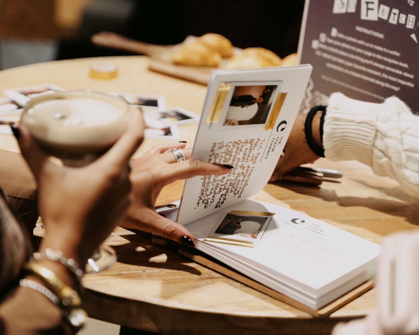 Hands paging through a custom keepsake photo book with instant film prints from The Color Connect
